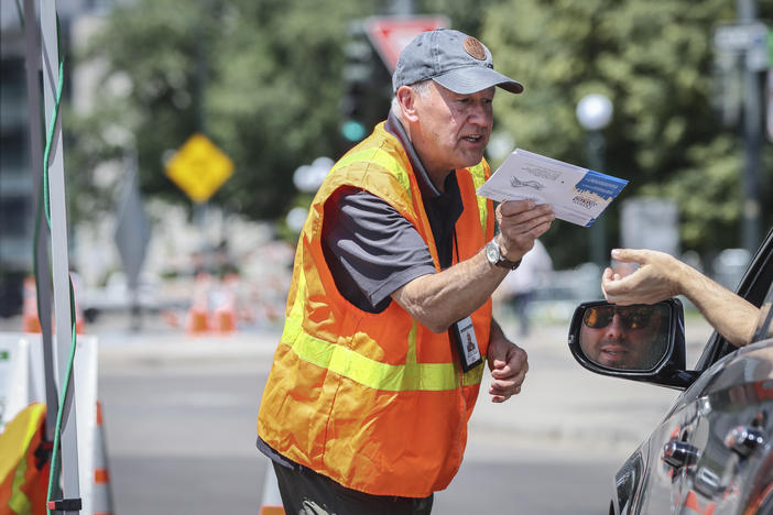 A voter hands over his ballot to an election judge at a drive-through ballot drop site in Denver on June 28, 2022. State election authorities accidentally sent voter registration information to 30,000 non-citizens who are ineligible to vote, which has fed conspiracy theories about the upcoming midterms.
