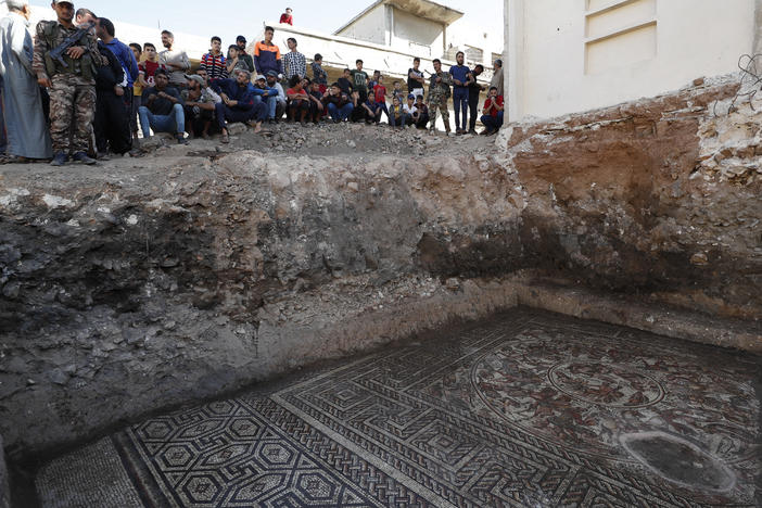 People look at a large mosaic that dates back to the Roman era in the town of Rastan, Syria, on Wednesday.