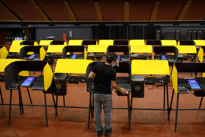 A poll worker sanitizes ballot marking machines at an early voting location in Inglewood, Calif., on Oct. 29, 2020. The Los Angeles County district attorney alleges that the CEO of Konnech, which makes scheduling software for poll workers, improperly gave Chinese contractors access to sensitive employee data.