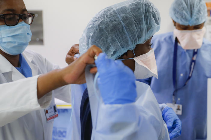 In this May 27, 2020 file photo, medical personnel adjust their personal protective equipment while working in the emergency department at NYC Health + Hospitals Metropolitan in New York.