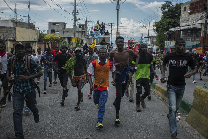 Protesters calling for the resignation of Haitian Prime Minister Ariel Henry run after police fired tear gas to disperse them in the Delmas area of Port-au-Prince, Haiti, Monday, Oct. 10, 2022.