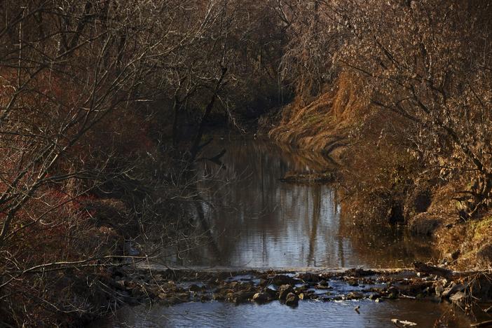 Water flows in Coldwater Creek on Thursday, Dec. 9, 2021, behind a row of homes at Belcroft Drive and Old Halls Ferry Road in Missouri's St. Louis County. Environmental investigation consultants have found significant radioactive contamination at an elementary school, which sits in the flood plain of Coldwater Creek which was contaminated by nuclear waste from weapons production during WWII.