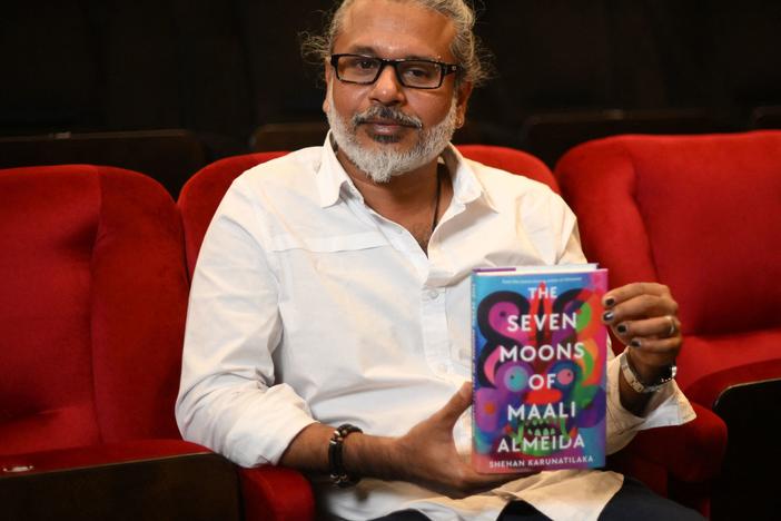 Sri Lankan author Shehan Karunatilaka holds his book <em>The Seven Moons of Maali Almeida</em> at the Shaw Theatre in London on Oct. 14. On Monday, his novel won the 2022 Booker Prize.