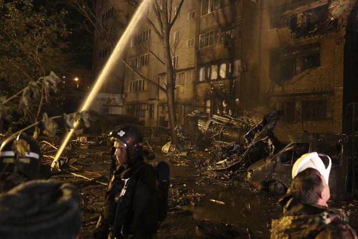Firefighters work at the scene after a warplane crashed into a residential area in Yeysk, Russia, Monday, Oct. 17, 2022.