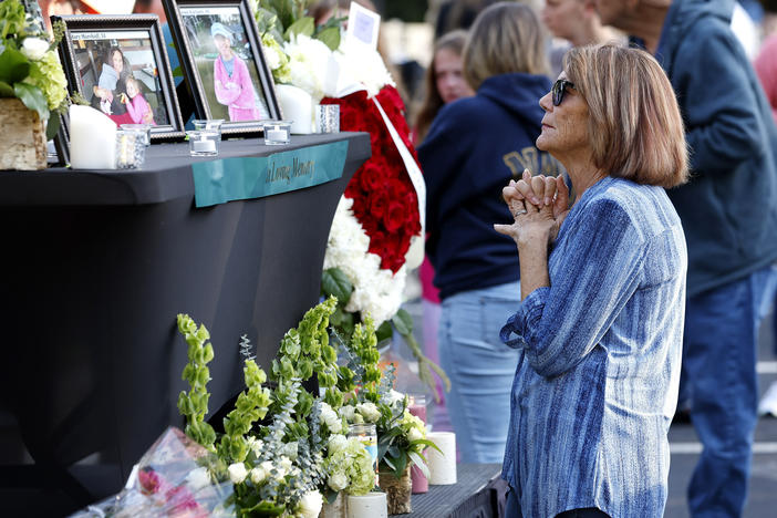 A woman stands before a photo of Raleigh shooting victim Susan Karnatz at a makeshift memorial.