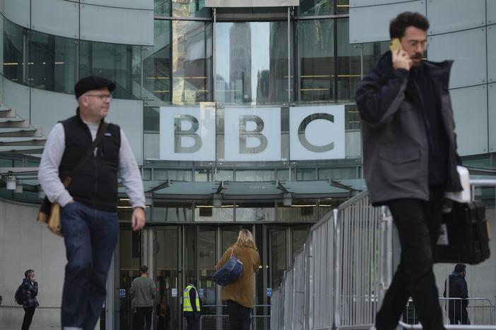 People walk past the BBC Headquarters in London on Tuesday as the BBC is celebrating 100 years of broadcasting.