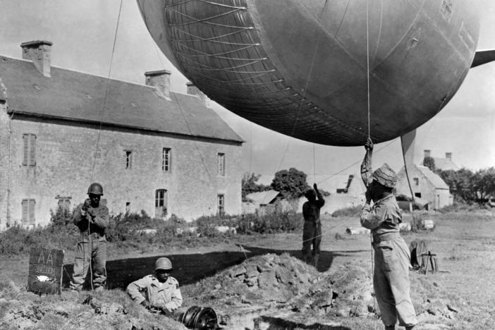U.S., Blacks soldiers of an anti-aircraft unit moor a barrage balloon to a site on the coast of Normandy, Summer 1944.