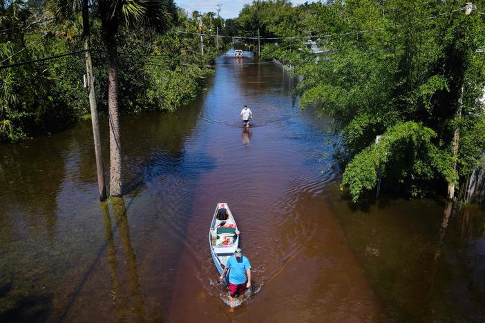 A man tows a canoe through a flooded street of his neighborhood in New Smyrna Beach, Fla., last month. <em>Vibrio vulnificus </em>thrives in warm, brackish floodwaters.