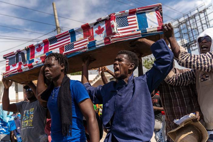 Demonstrators carry a coffin covered with American, Canadian and French flags and pictures of politicians as they protest on Jean-Jacques Dessalines Day in Port-au-Prince on Monday. Haitians protest against their prime minister and foreign countries as the nation celebrates the 216th anniversary of the assassination of Dessalines, a Haitian independence hero and founding father.