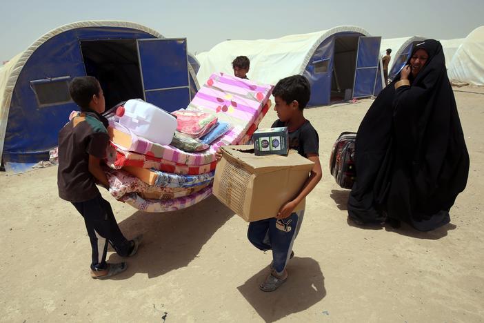 Iraqis displaced from the city of Fallujah collect aid distributed by the Norwegian Refugee Council, which has been awarded this year's $2.5 million Conrad N. Hilton Humanitarian Prize.