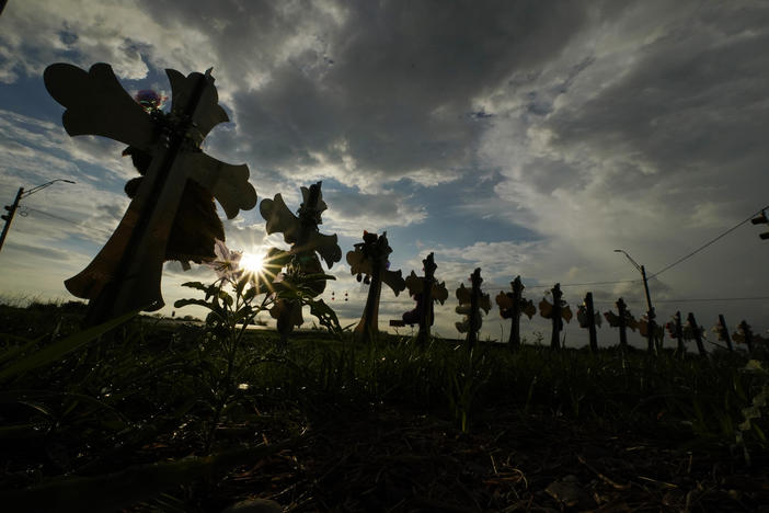 Vehicles on Aug. 25, 2022 pass crosses placed to honor the victims of the shootings at Robb Elementary School in Uvalde, Texas.