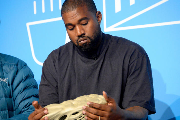 Ye, then known as Kanye West, holds a Yeezy sneaker while speaking onstage at the Fast Company Innovation Festival in 2019.