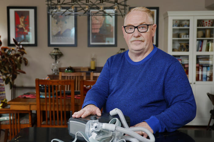 Jeffrey Reed, who experienced persistent sinus infections and two bouts of pneumonia while using a Philips CPAP machine, poses with the device Oct. 20 at his home in Marysville, Ohio.