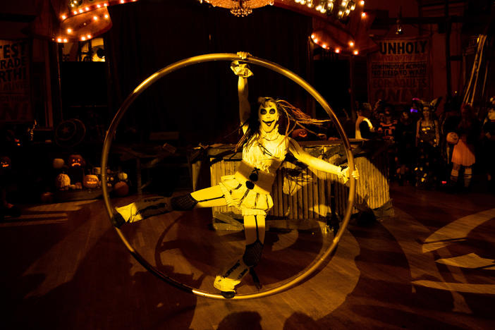 A performer swings around on a giant hula hoop as people cheer.