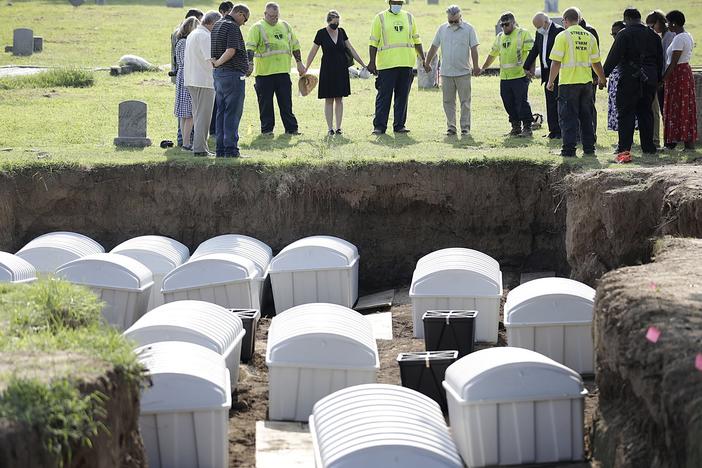 A group prays during a small ceremony as remains from a mass grave are re-interred at Oaklawn Cemetery on July 30, 2021, in Tulsa, Okla.