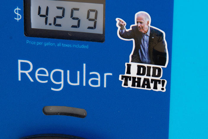 A gas pump displays current fuel prices, along with a sticker of President Biden, at a gas station in Arlington, Va., on March 16. The sticker says "I did that" — but the president wasn't responsible for rising prices then or falling prices now.