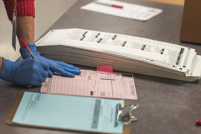 A poll worker handles ballots for the midterm election, in the presence of observers from both Democrat and Republican parties, at the Maricopa County Tabulation and Elections Center in Phoenix on Oct. 25.