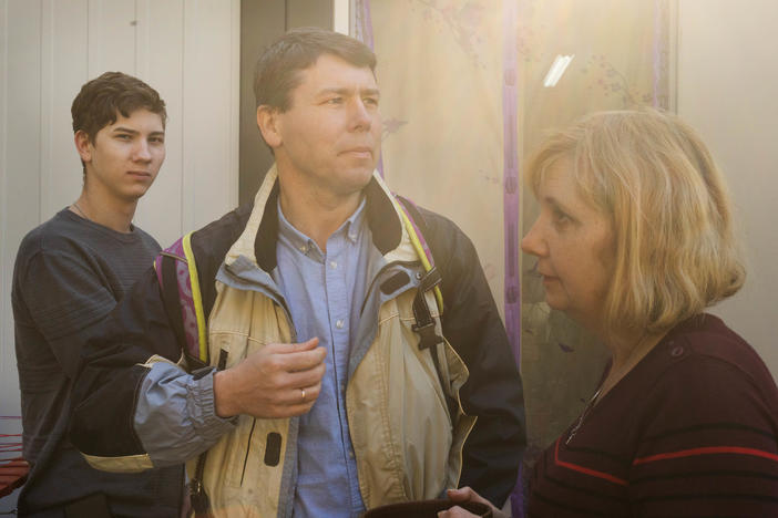 Volodymyr Korchevsky (center) stands with his son Bohdan, 18, and wife, Hanna Korchevska, outside their temporary home in Lviv. The Korchevsky family left the middle-class life they'd built in Mariupol and now months later, jobs gone, savings depleted and unable to afford rent, they are living in what's essentially a short shipping container, sandwiched between others, in a Lviv city park.