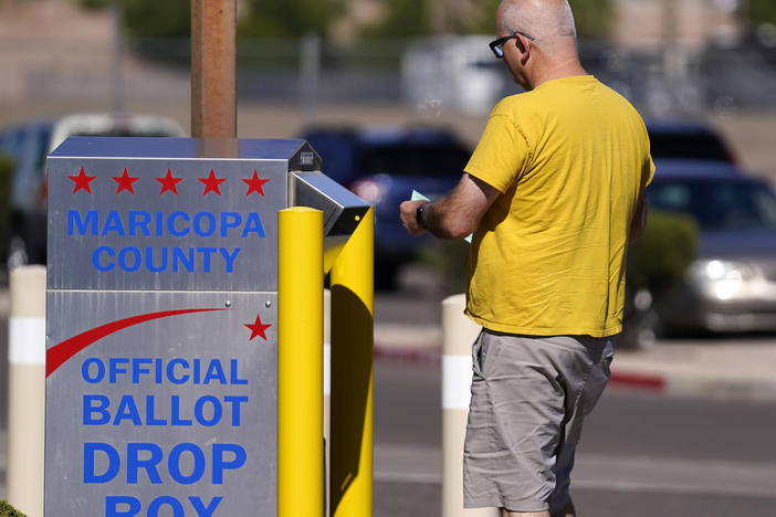 A voter places a ballot in an election voting drop box in Mesa, Ariz., on Friday.