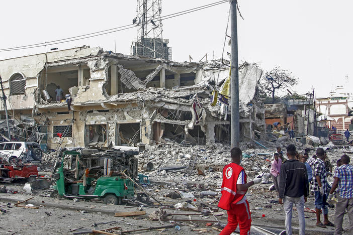 People observe a destroyed building and vehicles at the scene of an attack in Mogadishu, Somalia, on Saturday.