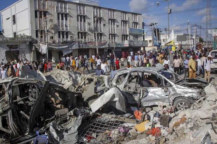 People walk among the destruction at the scene of the weekend's double car bomb attack Mogadishu, Somalia.