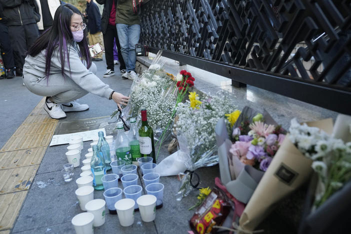 A woman places a bouquet of flowers to pay tribute for victims near the scene of the deadly crowd crush tragedy in Seoul, South Korea.