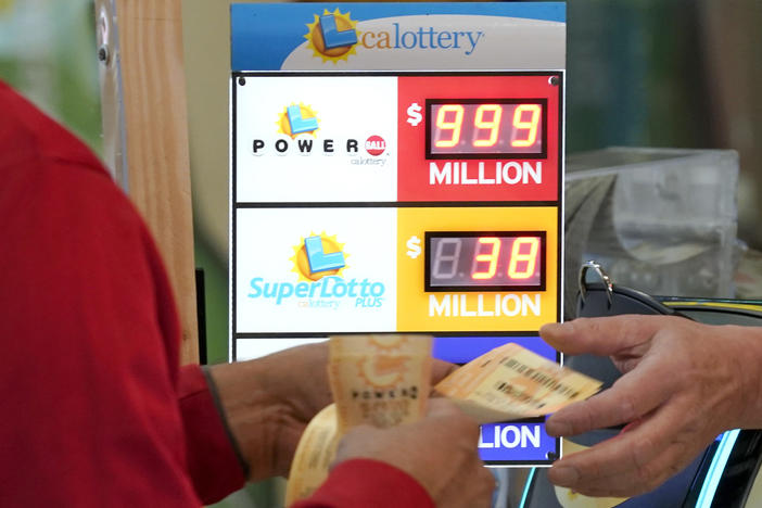 A customer is handed Powerball lottery tickets to purchased at Lichine's Liquor & Deli in Sacramento, Calif., Monday, Oct. 31, 2022. The jackpot for Monday night's drawing soared to $1 billion after no one matched all six numbers in Saturday night's drawing. It's the fifth-largest lottery jackpot in U.S. history.