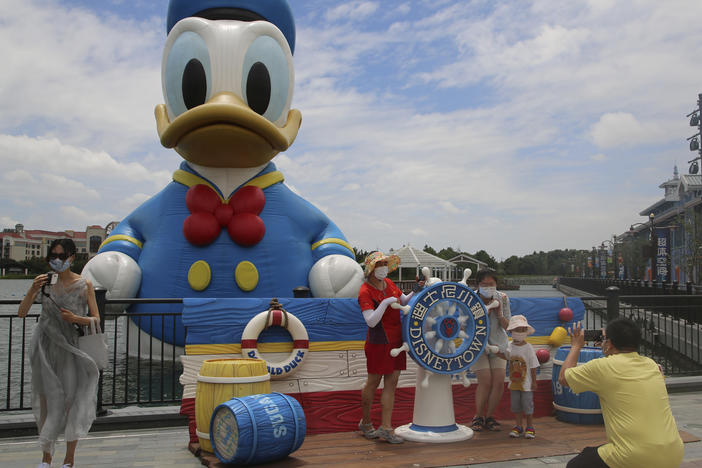 Visitors pose for photos outside the Disney Resort theme park in Shanghai in June.