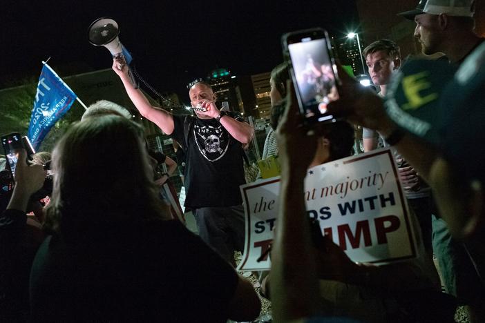 A man shouts into a bullhorn as Trump supporters gather in front of the Maricopa County Elections Department in Phoenix, where ballots were being counted following the 2020 presidential election. Federal officials have warned about violence erupting after this year's election, with experts particularly concerned about the period after Nov. 8.