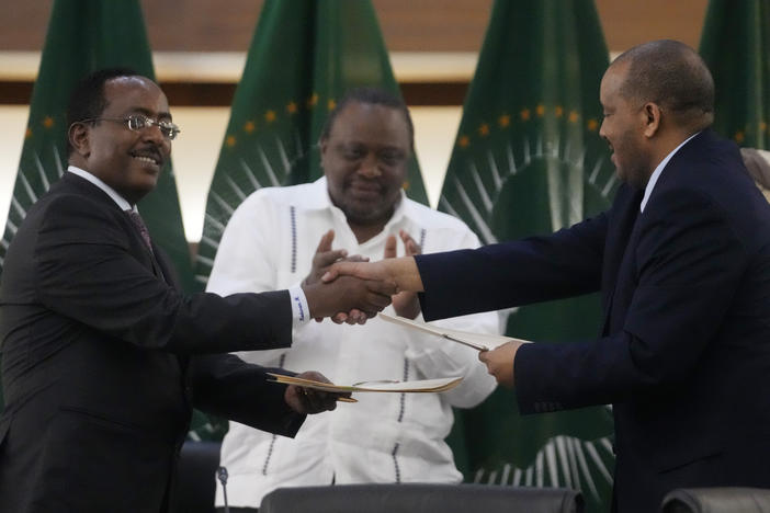 Lead negotiator for Ethiopia's government Redwan Hussein (left) shakes hands with lead Tigray negotiator Getachew Reda, as Kenya's former president, Uhuru Kenyatta looks on, after the peace talks in Pretoria, South Africa, on Wednesday.