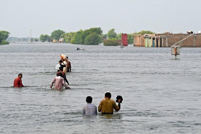 People wade through floodwaters in Pakistan after heavy monsoon rains this summer. Scientists say climate change helped drive the deadly floods.
