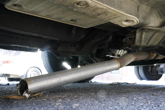 The exhaust pipe of an abandoned car missing its catalytic converter, rests on the ground in Philadelphia, Thursday, July 14, 2022.