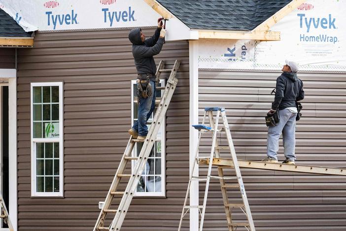 Workers attach siding to a house at a new home construction site in Trappe, Maryland, on October 28, 2022. Rising interest rates could mean slowing job growth in construction and manufacturing.