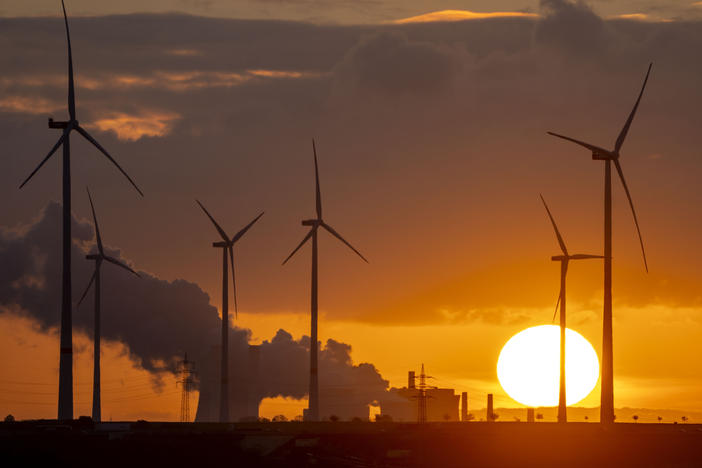 Steam rises from the coal-fired power plant with wind turbines nearby in Niederaussem, Germany, as the sun rises on Nov. 2, 2022.