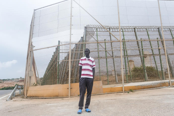 Steven Khon Khon, of South Sudan, stands on the Spanish side of a four-layered fence dividing Nador, Morocco from Melilla, Spain on October 11. On June 24, Khon Khon and many others trying to get to Europe charged the fence. They were beaten back by Moroccan authorities. Dozens were killed. Khon Khon made it to Spain that day, but his brother remained stuck in Morocco.