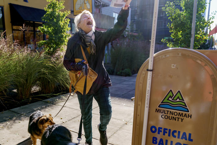 Perrin Thompson kisses her ballot for luck and does a little dance before dropping it into a drop site outside of the Multnomah County Elections Division in Portland, Ore., Nov. 8, 2022.
