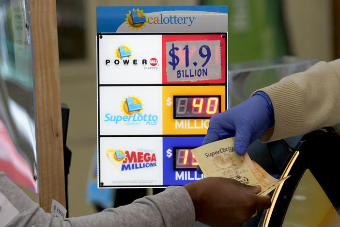 A customer is handed Powerball tickets purchased at Lichine's Liquor & Deli in Sacramento, Calif., Monday, Nov. 7, 2022. Monday night's drawing is estimated to be a record $1.9 billion.