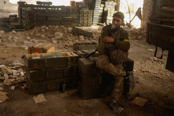 A Ukrainian soldier sits on captured Russian mortar shells in the village of Blahodatne, retaken by the Ukrainian Armed Forces a day ago, in Kherson region on Friday. Ukraine's president said special units entered Kherson city and other troops were on the approach.