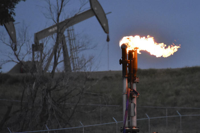 A flare to burn methane from oil production is seen in August 2021 on a well pad near Watford City, N.D.