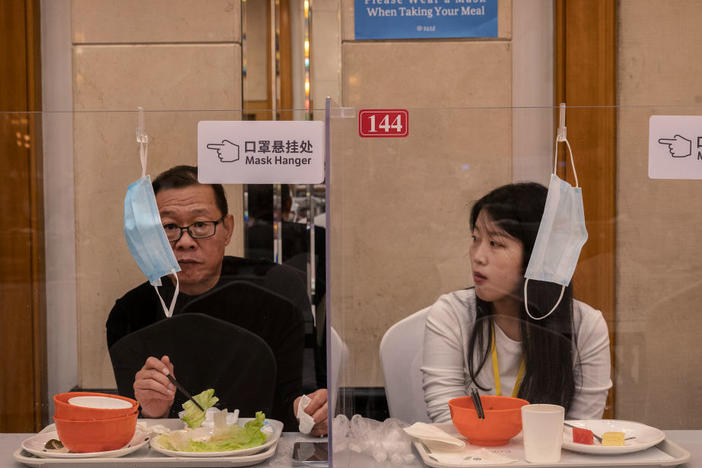 People eat lunch separated by plexiglass to prevent the spread of COVID-19 at the 20th National Congress of the Communist Party of China on Oct. 20 in Beijing. China is beginning to ease its strict COVID policies to help the stifled economy.