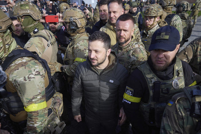 In this photo provided by the Ukrainian Presidential Press Office, Ukrainian President Volodymyr Zelenskyy, surrounded by his guards, walks on central square during his visit to Kherson on Monday.