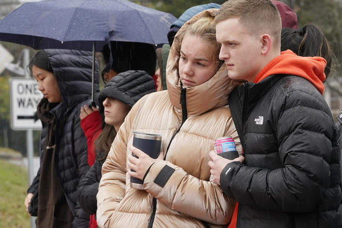 Mourners look over flowers that line a bridge near the scene of a shooting on the grounds of the University of Virginia Tuesday Nov. 15, 2022, in Charlottesville. Va.