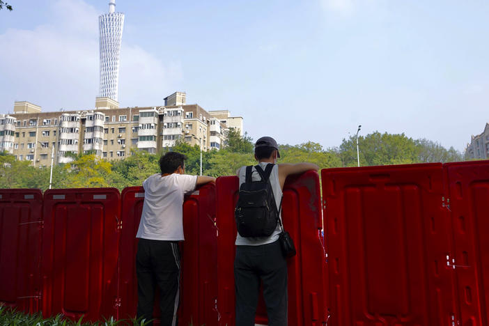 Residents look out from barriers around the recently locked down Haizhu district in Guangzhou in southern China's Guangdong province Friday, Nov. 11, 2022.