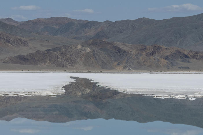 Salt deposits float as the mountains are reflected in a lithium brine evaporation pool at Silver Peak lithium mine in Silver Peak, Nev. on Oct. 6, 2022.