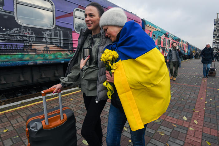 Oksana Shevliuha, 51, wears a Ukrainian flag as she greets her daughter, Anastasia, who arrived on the first train to reach liberated Kherson on Saturday. They had not seen each other for six months. The first Ukrainian Railways train arrived in Kherson following a Russian occupation that lasted more than eight months.