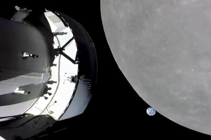 This screengrab from NASA TV shows NASA's Orion capsule, left, nearing the moon, right, on Monday. At center is Earth.
