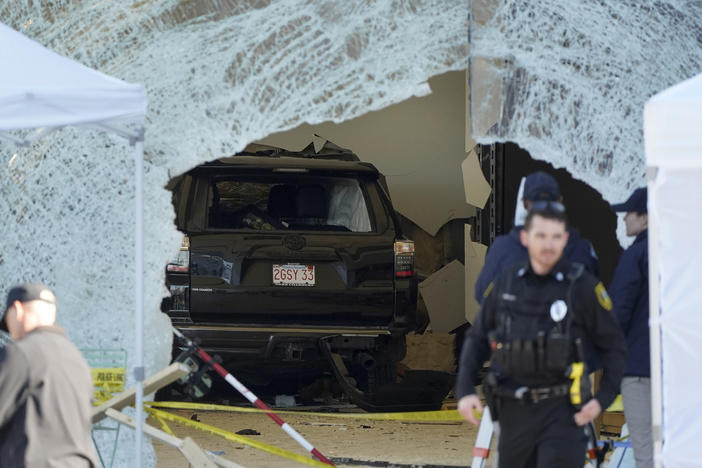 An SUV sits inside an Apple store behind a large hole in the glass. One person was killed and 16 others were injured Monday when the SUV crashed into the store, authorities said.