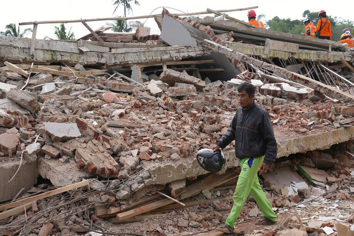 Enjot, 45, who lost his house and some of his relatives, walks on Tuesday past the rubble of a building collapsed in Monday's earthquake in Cianjur, West Java, Indonesia.
