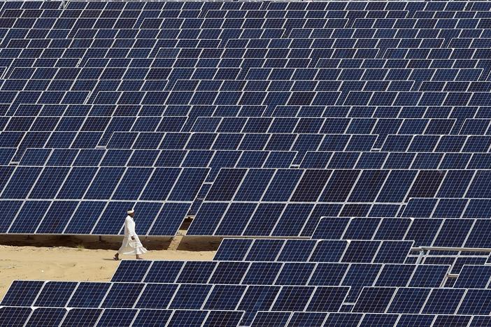 A worker walks past lines of solar panels at the Roha Dyechem solar project in the western northwest Indian state of Rajasthan.