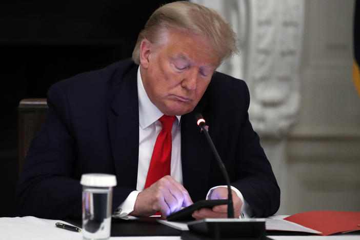 Former President Donald Trump looks at his phone during a roundtable with governors in the State Dining Room of the White House in Washington, June 18, 2020.